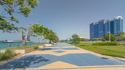 Poster - Corniche boulevard beach park along the coastline in Abu Dhabi timelapse hyperlapse with skyscrapers on background.