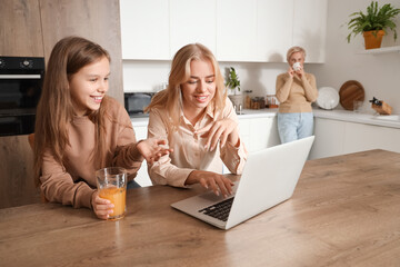 Sticker - Little girl with her mom using laptop in kitchen