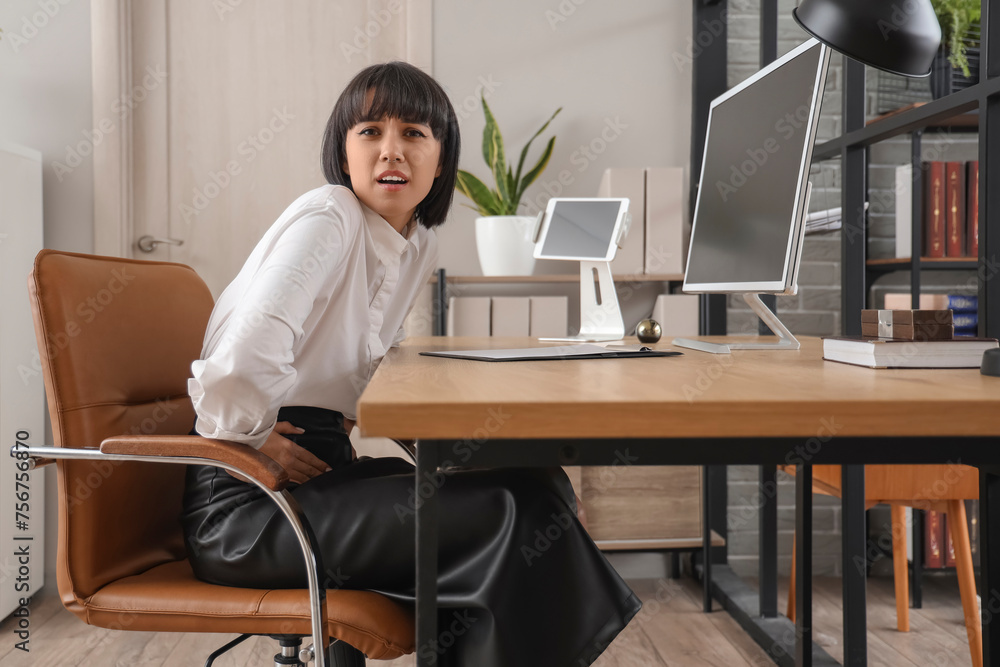 Young businesswoman suffering from bellyache in office