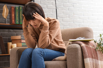 Sticker - Young woman suffering from headache in armchair at home