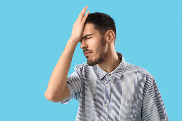 Canvas Print - Young man suffering from migraine on blue background