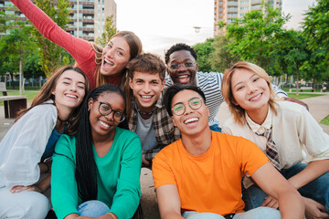 Big group of young adult real people smiling and having fun outdoors at vacations. Portrait of happy friends laughing. University teenage students on a social gathering. Multiracial teenagers meeting