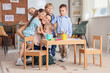 © Pixel-Shot - Little children hugging nursery teacher during art lesson in kindergarten