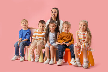 Wall Mural - Little children with nursery teacher sitting on pink background