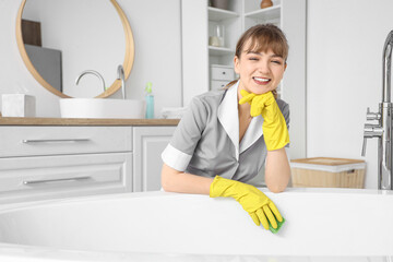 Wall Mural - Young chambermaid cleaning bathtub in bathroom