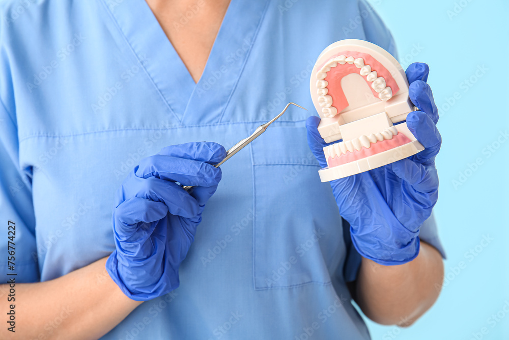 Female dentist with plastic jaw on blue background, closeup