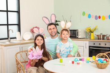 Canvas Print - Father with children sitting at table in kitchen decorated for Easter celebration