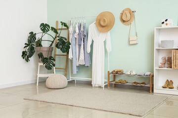 Poster - Interior of light room with rack of stylish clothes, houseplant and shelf with shoes