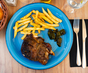 Wall Mural - Baked pork knuckle with peppers and French fries dished up in a plate on the laid restaurant table