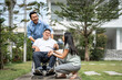 © Kawee - Asian attractive family walking with young son on wheelchair in garden.