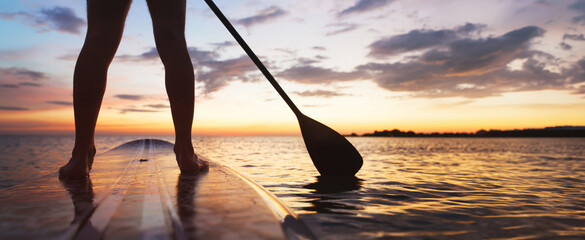 Wall Mural - SUP, paddle board on the beach, close up of standing  legs and paddle, banner background