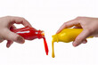 Hands squeezing ketchup and mustard out of plastic bottles, isolated on white background
