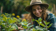 A woman is smiling and wearing a straw hat while tending to a garden