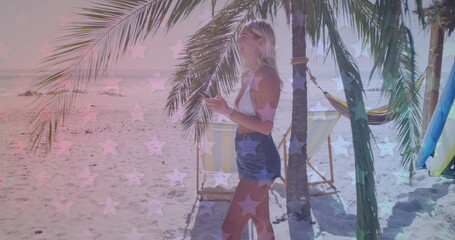 Wall Mural - Young Caucasian woman stands by a palm tree on the beach