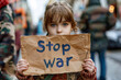 Child's Message: A young girl with earnest eyes holds up a heartfelt plea — 'Stop war' — amidst a bustling cityscape