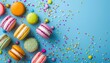 Colorful macaroons and sugar sprinkles on blue background with empty space