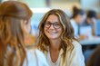 © Sariyono - Smiling young woman with glasses engaged in conversation at a social gathering, portraying warmth and friendliness