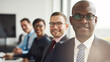 © Flamingo Images - Group of multicultural businesspeople working together in a modern workplace. Successful business team smiling cheerfully while sitting in a row at a boardroom table and looking direct into the camera