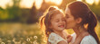 Mother kissing her daughter on the cheeks, copy space background for mother's day