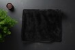 A mockup of a black beach towel with a soft texture is shown unfolded on the floor The top view displays a shaggy fur bath towel with a textured design This domestic cloth kitchen ov