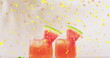 Image of confetti falling and cocktails on white background