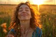 © lili - Backlit Portrait of a calm happy smiling free woman with her eyes closed enjoying a beautiful moment of life in a field at sunset