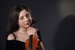 young pretty girl with a violin on a dark background. a violinist's dreamy view of the big stage and success.