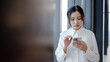 © TeTe Song - Upset stressed asian woman holding cellphone disgusted with message she received in office, Sad looking face expression emotion feeling reaction perception body language, Dissatisfied, confusingly