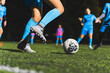 © PoppyPix - closeup shot of girls with blue uniforms practicing football on a green field at night, girls sport. High quality photo