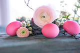 Fototapeta Tulipany - Pink easter eggs in front of a herb nest with spring flowers on weathered rustic wooden table. Close-up with short depth of field. Easter background.