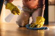 Cropped picture of a woman kneeling and cleaning floor with spray and rag.