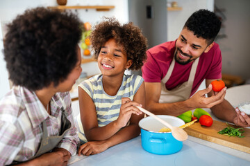 Wall Mural - Happy african american parents and child having fun preparing healthy food in kitchen