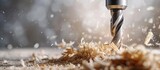 Fototapeta  - steel drill with wood chippings flying off. Sawdust flies off a spinning drill boring a hole into a wooden board.