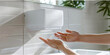 Frau im Badezimmer trocknet sich die Hände unter elektrischem Händetrockner