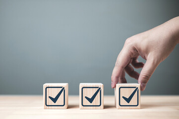 Inspection and certification of standards. Check mark on wooden block. Concept of item verification, jobs list, and product quality certification.