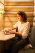 © carlesmiro - Side view of focused young beautiful female typing on laptop while working on project in cozy workplace with wooden interior.