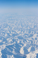 Wall Mural - aerial view of snow-capped mountains. winter snowy mountain landscape. air travel to the far north o