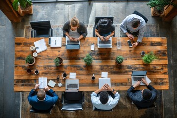 Business professionals working at conference table with laptops and papers in modern office setting