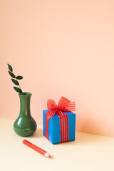 Wall Mural - Blue gift box, vase of eucalyptus leaf, red colored pencil on ivory table. pink wall background