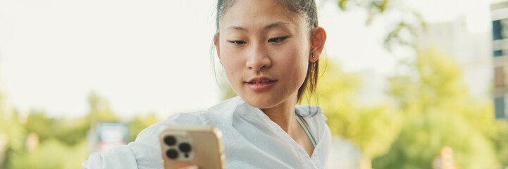 Poster - Young woman sitting on bench and using mobile phone, Panorama