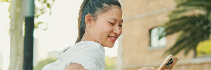 Poster - Young woman sitting on bench and using mobile phone, Panorama