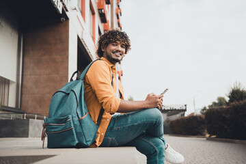 Sticker - Photo of positive glad man sitting outdoors dormitory or university building spending free time reading scrolling instagram