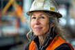 Mature woman in construction gear confidently smirking on job site
