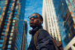 Urban Vibes: Stylish Black Man Walking with Phone and Backpack in Cityscape