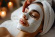 Skincare Specialist at Spa Salon Enhancing Facial Treatment with Sheet Mask for Relaxing Client. Young Woman Enjoying Peeling and Antioxidant Beauty Ritual. Skin Care Concept.