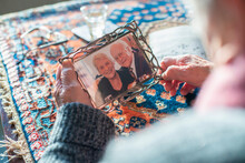 Elderly hands holding a treasured photo frame with an image of an older couple
