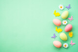 Fototapeta Nowy Jork - Happy Easter background. Eggs, rabbit, spring flowers and butterfly. Flat lay image at green background.