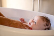 © Connect Images - A baby enjoying bath time, gazing up with a look of contentment.