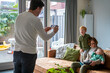 © Connect Images - Family moment captured indoors as a man takes a photo of a woman with two young children on a cozy sofa.