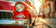 A vintage red car parked on a sunny city street, with a close-up on its shiny chrome headlight and grille, 